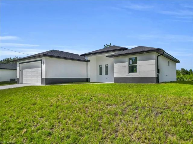 View of front of home with an attached garage, a front yard, concrete driveway, and stucco siding