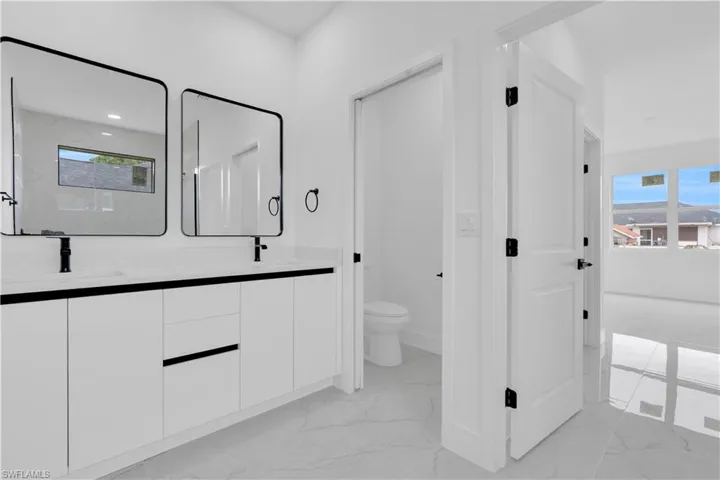 Bathroom with light marble finish flooring, double vanity, and a marble finish shower