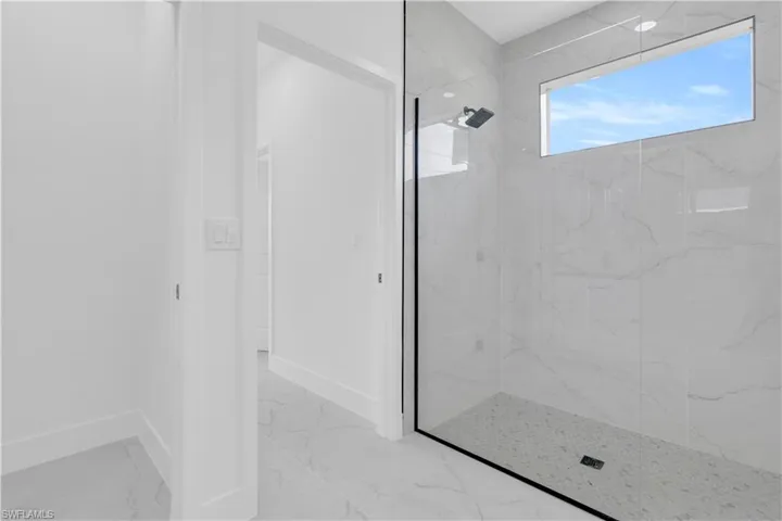 Full bathroom featuring light marble finish flooring and a marble finish shower