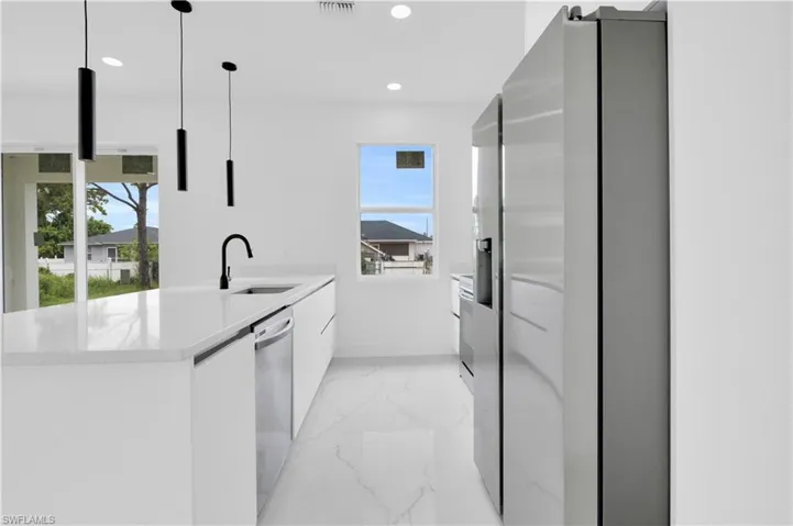 Kitchen featuring modern cabinets, stainless steel appliances, a peninsula, white cabinetry, and light stone counters