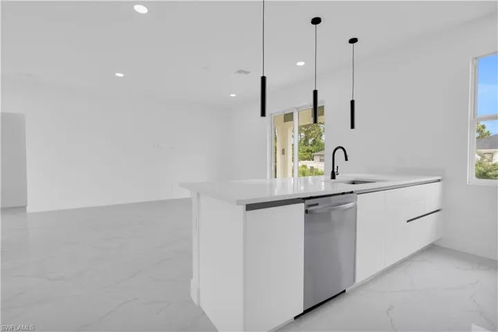Kitchen featuring white cabinetry, a peninsula, light marble finish floors, modern cabinets, and dishwasher
