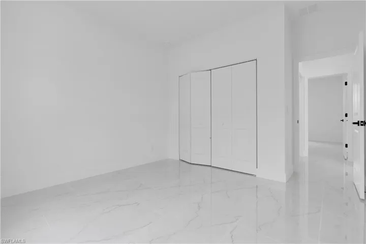 Unfurnished bedroom featuring light marble finish flooring and a closet