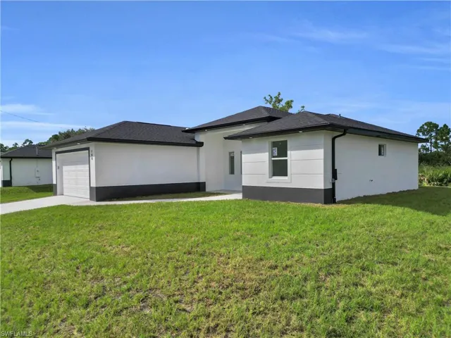 View of front of home featuring a front yard, a garage, concrete driveway, and stucco siding