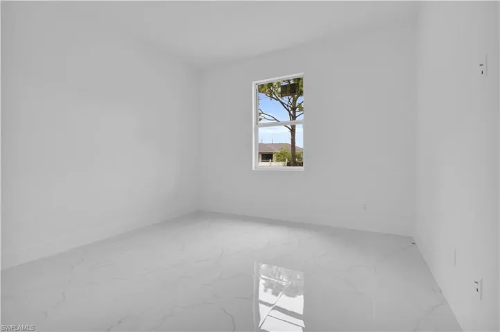 Unfurnished room featuring light marble finish floors and baseboards