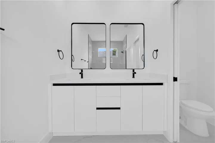 Bathroom featuring double vanity and light marble finish flooring