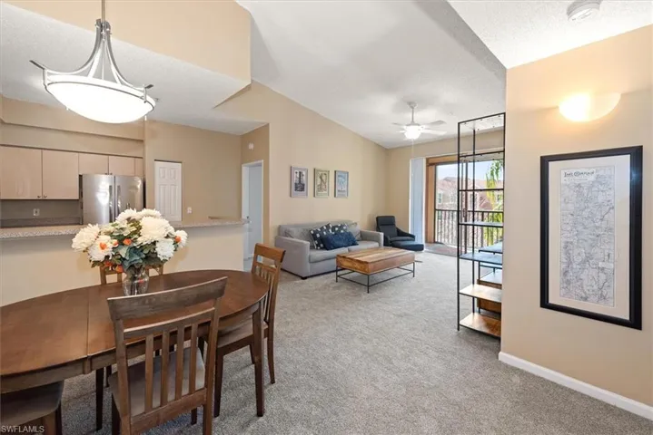 Dining area and living room featuring new light carpet and ceiling fan