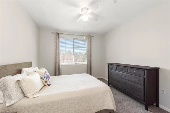 Primary bedroom with newer carpet, a ceiling fan, and vaulted ceiling