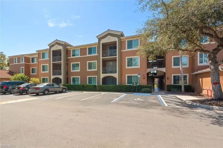 View of condominium building featuring uncovered parking
