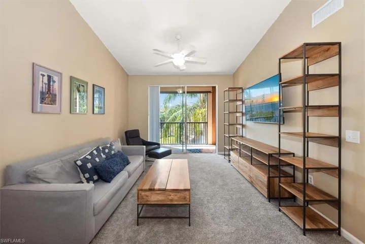 Living area featuring new carpet, vaulted ceiling and fan
