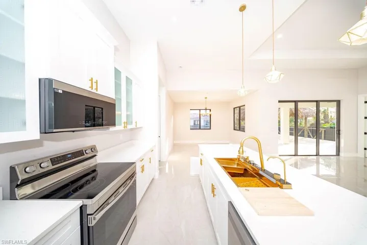 Kitchen with appliances with stainless steel finishes, decorative light fixtures, white cabinets, and glass insert cabinets