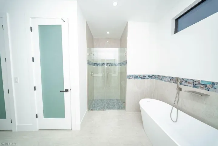 Full bathroom with a stall shower, a soaking tub, recessed lighting, tile walls, and marble finish floors
