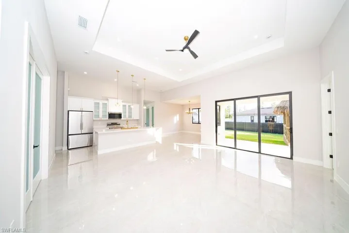 Unfurnished living room with ceiling fan, a chandelier, and light marble finish flooring