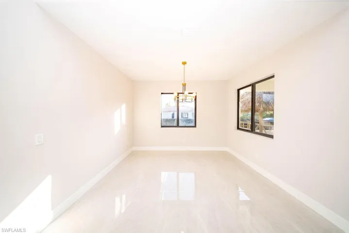 Unfurnished room featuring baseboards and a chandelier