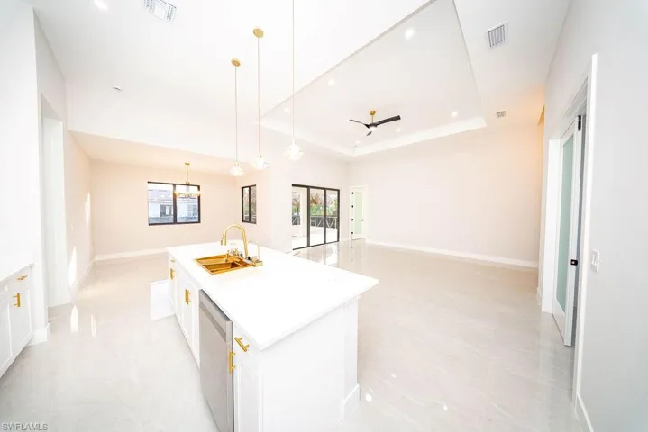 Kitchen featuring white cabinetry, open floor plan, dishwasher, pendant lighting, and a raised ceiling