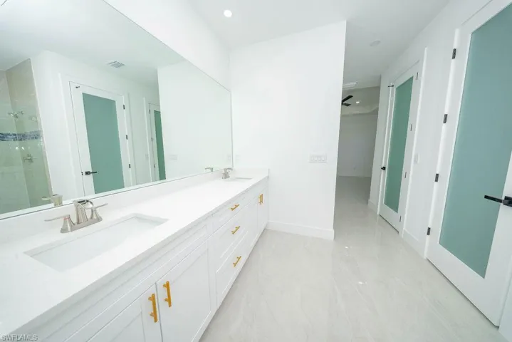 Bathroom with double vanity, a shower stall, and recessed lighting