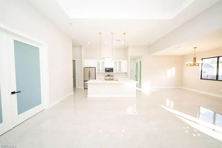 Unfurnished living room featuring a chandelier, a skylight, and light marble finish flooring