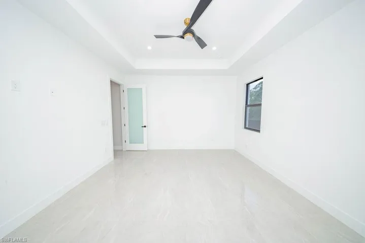 Empty room with ceiling fan, a tray ceiling, and recessed lighting