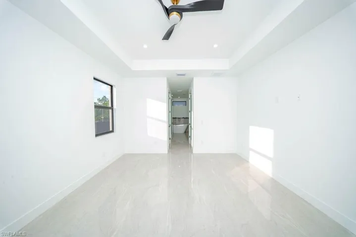 Unfurnished room featuring a raised ceiling, a ceiling fan, and recessed lighting
