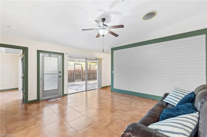 Living room featuring ceiling fan, lofted ceiling, and light tile patterned floors