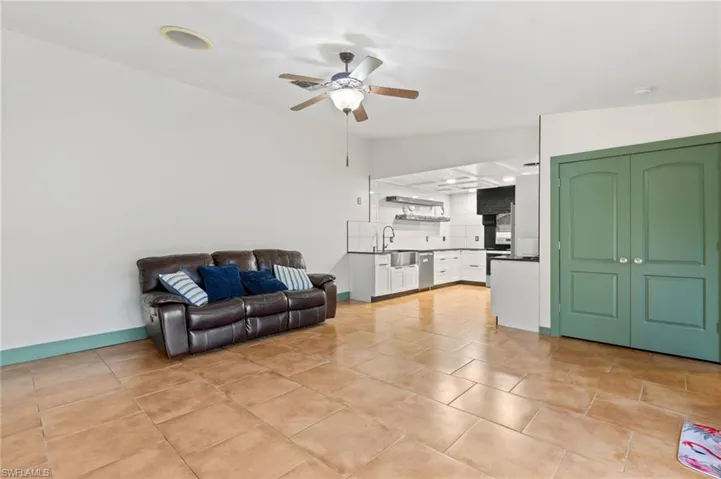 Living room with sink, light tile patterned floors, lofted ceiling, and ceiling fan