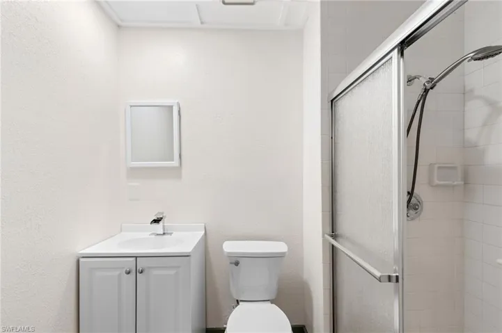 Bathroom with a shower with door, toilet, and vanity