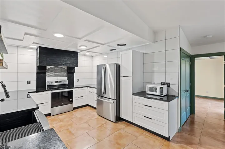Kitchen featuring light tile patterned flooring, white cabinetry, tasteful backsplash, and stainless steel appliances