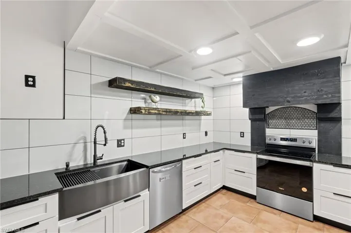 Kitchen featuring white cabinets, stainless steel appliances, dark stone countertops, and sink