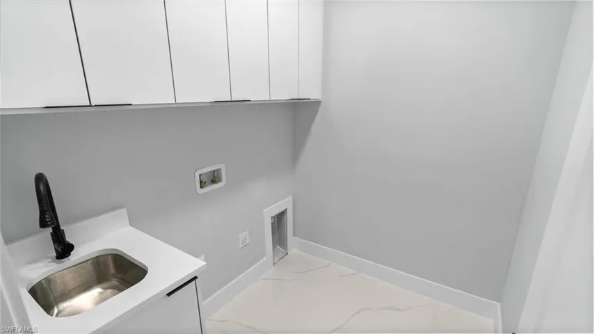 Washroom with cabinet space, washer hookup, and marble look tiles