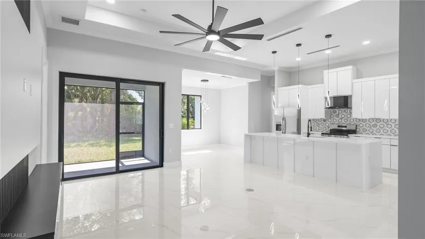 Kitchen with appliances with stainless steel finishes, tasteful backsplash, a ceiling fan, light countertops, and ornamental molding