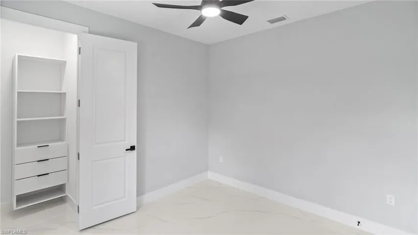 Unfurnished bedroom featuring marble look tiles and ceiling fan