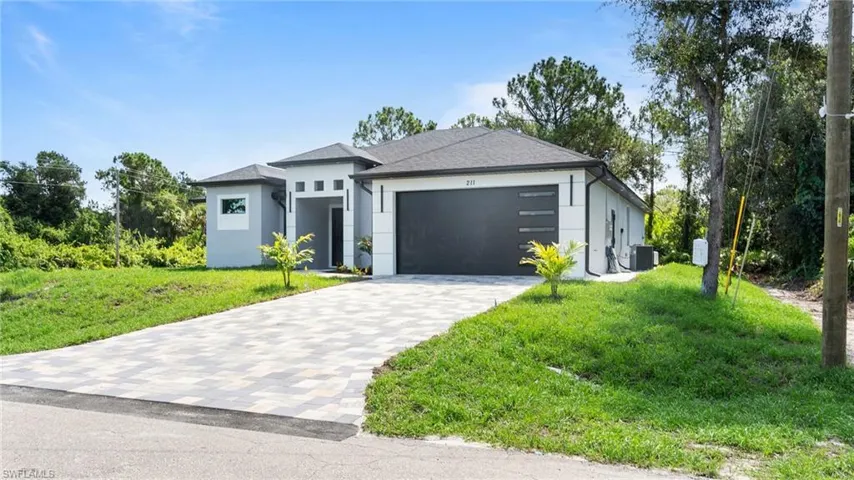 View of front of property featuring an attached garage, stucco siding, decorative driveway, and a front lawn