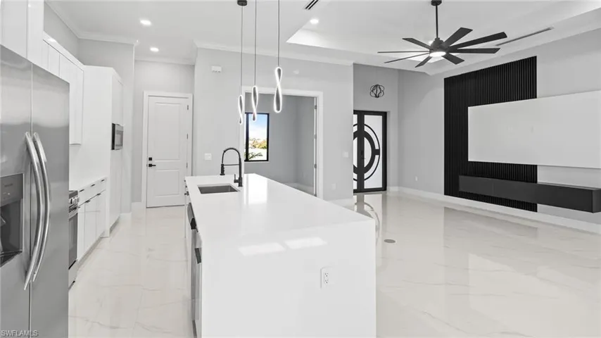 Kitchen with modern cabinets, stainless steel appliances, light marble finish floors, a kitchen island with sink, and a ceiling fan