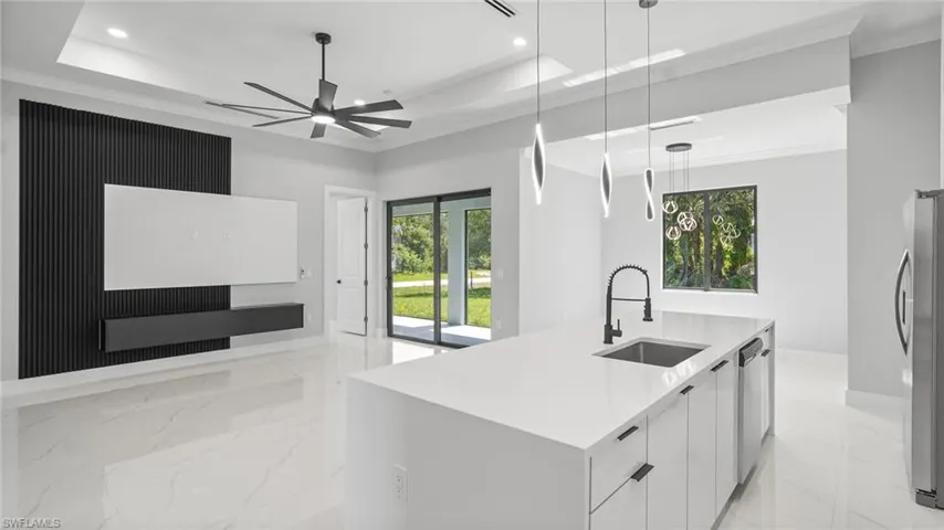 Kitchen with modern cabinets, a tray ceiling, open floor plan, recessed lighting, and a ceiling fan