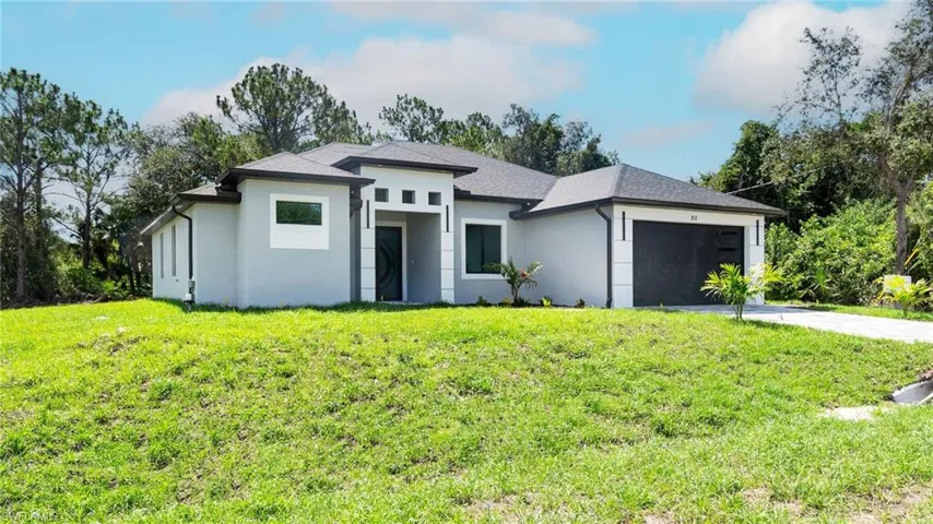 Prairie-style house with an attached garage, concrete driveway, stucco siding, and a front lawn