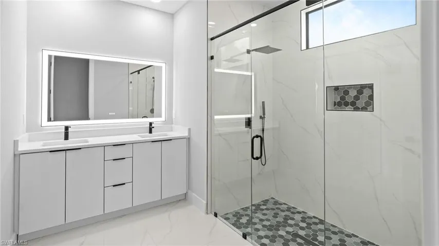 Bathroom featuring a marble finish shower, double vanity, and marble finish flooring