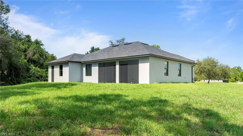 Back of house with stucco siding and a lawn