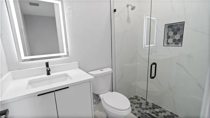 Bathroom featuring vanity and a marble finish shower