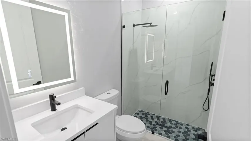 Full bath featuring a marble finish shower and vanity