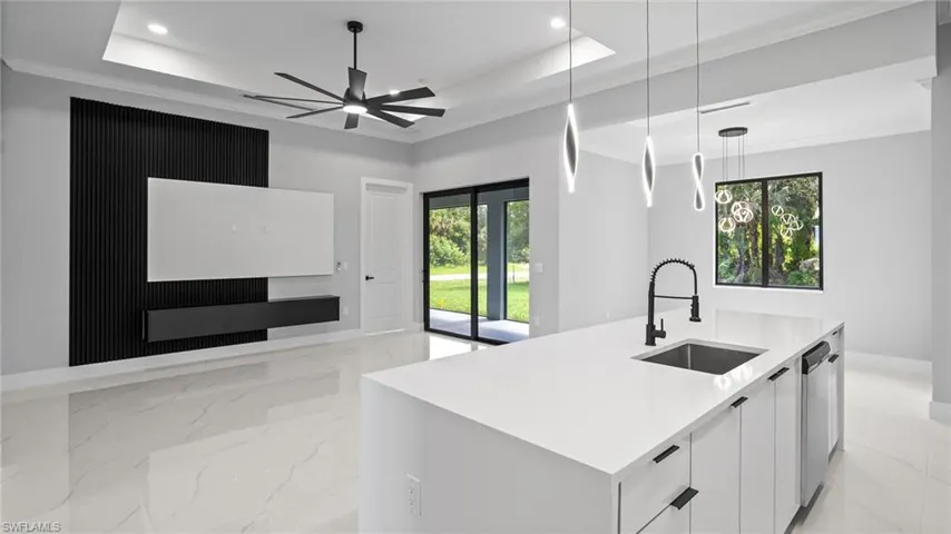 Kitchen with modern cabinets, light marble finish floors, open floor plan, a raised ceiling, and decorative light fixtures