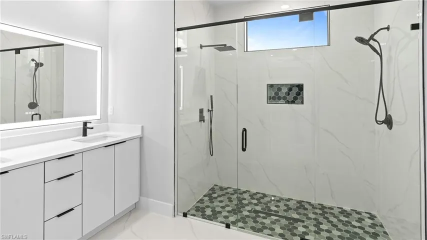 Full bathroom featuring a marble finish shower, double vanity, and marble finish flooring