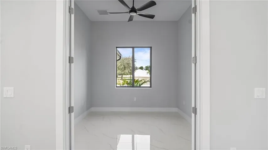 Spare room featuring marble finish floors and ceiling fan