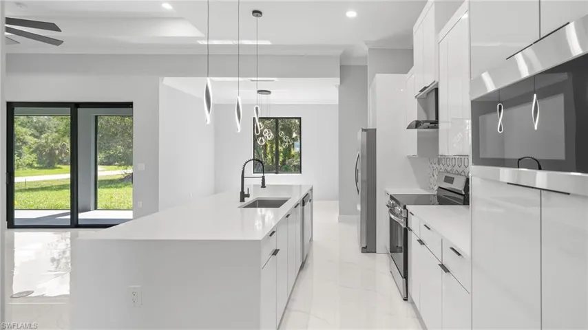 Kitchen featuring appliances with stainless steel finishes, modern cabinets, light marble finish floors, recessed lighting, and ornamental molding