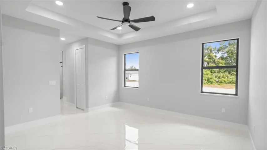 Spare room with recessed lighting, a raised ceiling, light marble finish floors, and a ceiling fan
