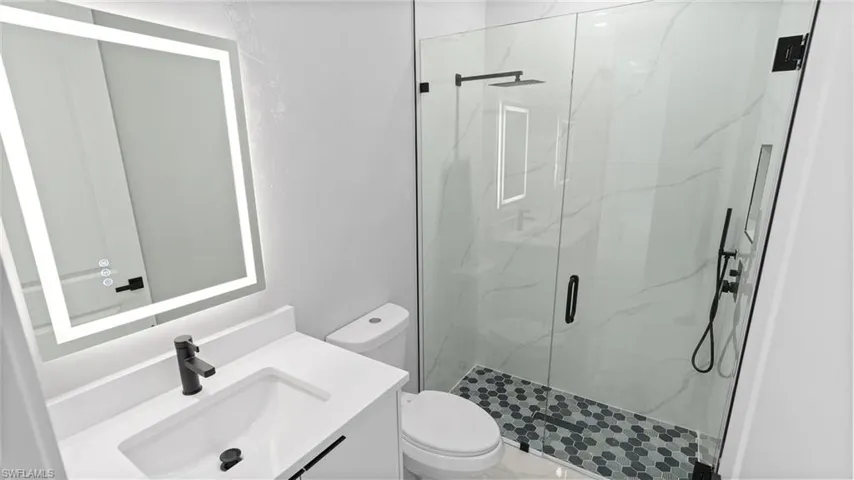 Bathroom featuring a marble finish shower and vanity