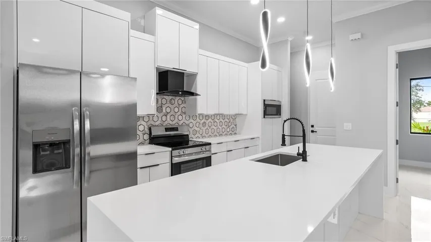 Kitchen with appliances with stainless steel finishes, light marble finish floors, white cabinetry, modern cabinets, and crown molding