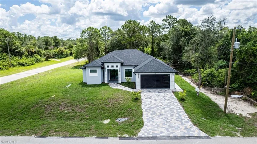 View of front of home with an attached garage, a front lawn, and decorative driveway