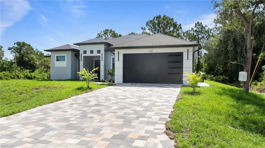 Prairie-style home featuring decorative driveway, stucco siding, a front yard, and an attached garage