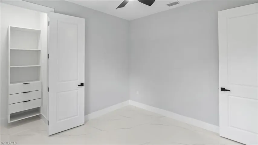 Unfurnished bedroom featuring marble look tile flooring and a ceiling fan