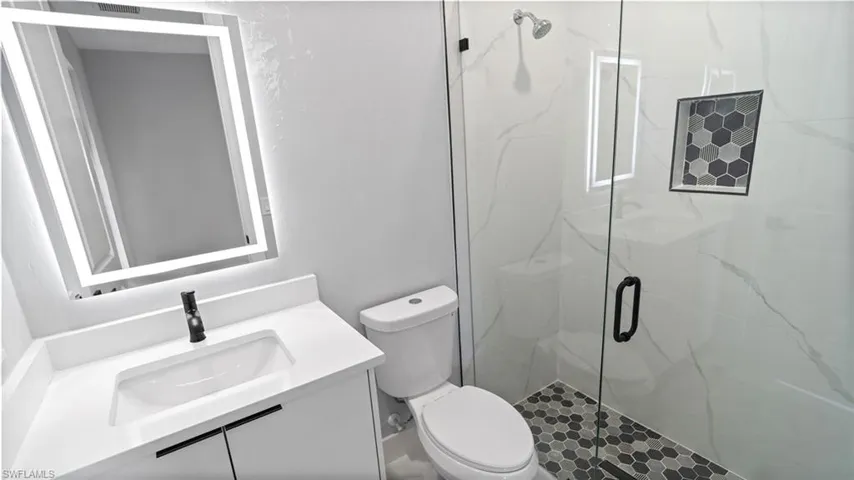 Bathroom featuring a marble finish shower and vanity