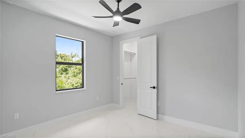 Unfurnished bedroom featuring light marble finish floors and ceiling fan